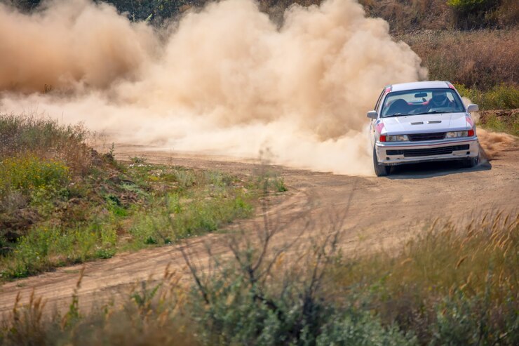 Foto dia ensolarado de verão. pista de rali empoeirada. carro esporte faz muita poeira na curva 01