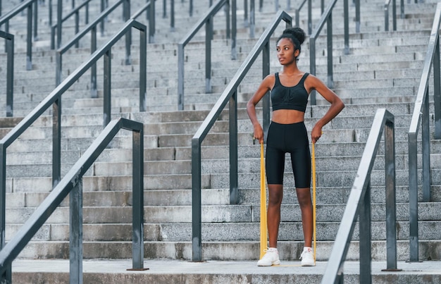 Día de estiramiento Joven mujer afroamericana en ropa deportiva tiene entrenamiento al aire libre