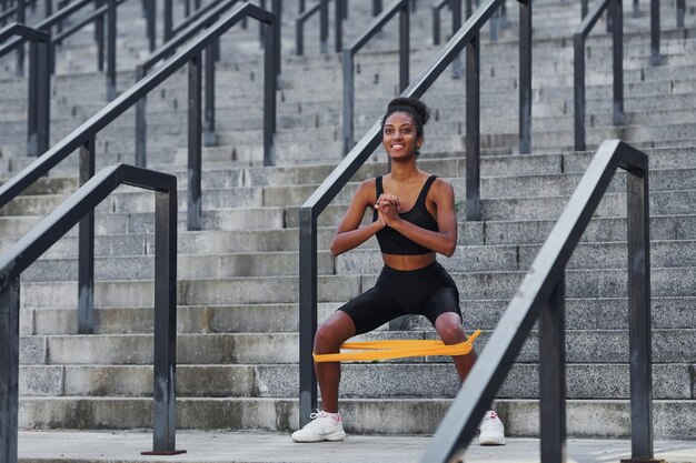 Día de estiramiento Joven mujer afroamericana en ropa deportiva tiene entrenamiento al aire libre