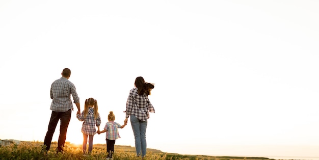 Día de la familia Padres e hijos miran el cielo del atardecer Vista desde atrás Concepto de relación feliz de hijas y papá con mamá Lugar para textBanner