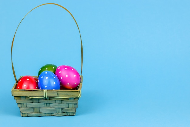 Día de fiesta, evento y concepto de Pascua - huevos de Pascua en una cesta en un fondo azul.