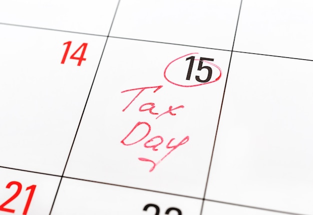 Día de impuestos escrito en el calendario y marcado con un círculo el día 15 por concepto de fecha límite de pago de impuestos