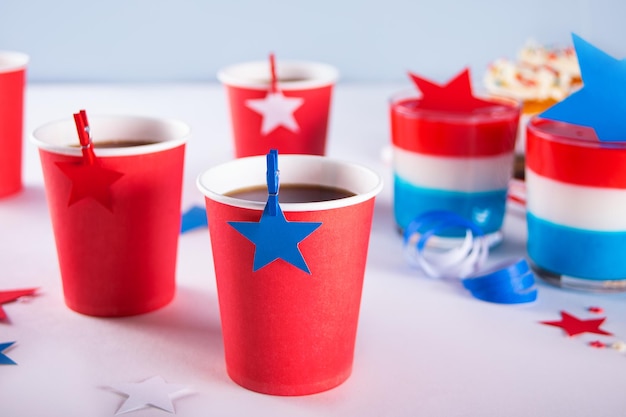 Día de la Independencia 4 de julio EE. UU. Fiesta patriótica estadounidense con símbolos estadounidenses Taza de papel con bebidas y postre sabroso gelatina de colores en capas con estrellas en el fondo