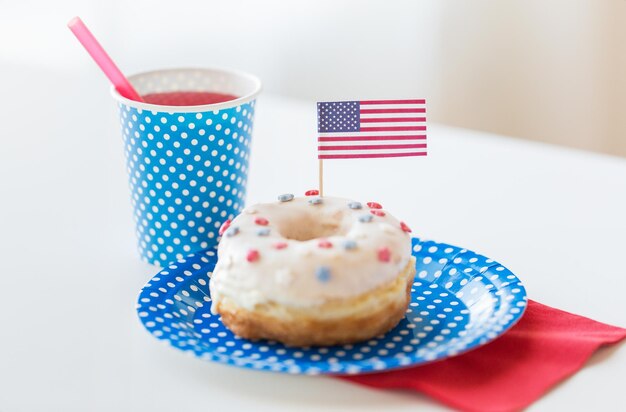 día de la independencia americana, celebración, patriotismo y concepto de vacaciones - cierre de donut dulce glaseado decorado con bandera y jugo en vajilla desechable en la fiesta del 4 de julio