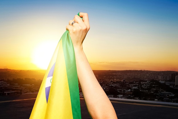 Día de la Independencia de Brasil Mujer madura con cabello gris sosteniendo la bandera de Brasil sobre fondo cinematográfico