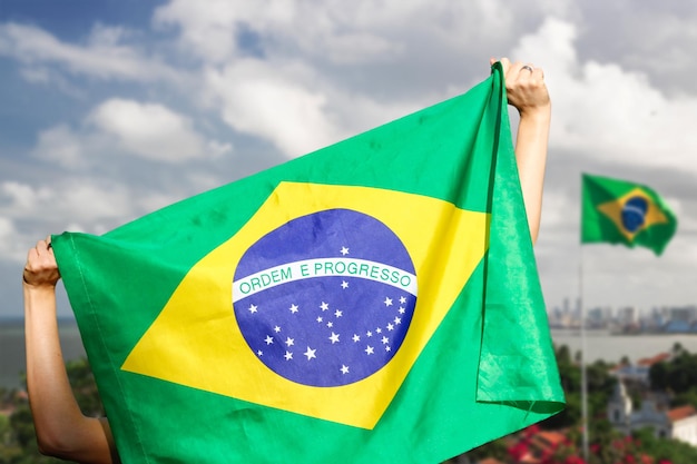 Día de la Independencia de Brasil Mujer madura con cabello gris sosteniendo la bandera de Brasil sobre fondo cinematográfico