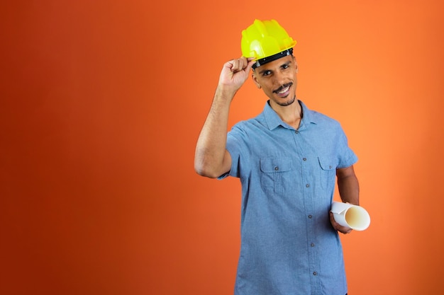 Día de los ingenieros Hombre negro en casco de seguridad y camisa azul aislado en naranja