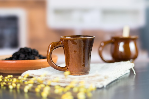 Día internacional del café bebida tradicional colombiana primer plano de taza y granos de café tostados en la mesa de la cocina negra decorada con flores en el fondo