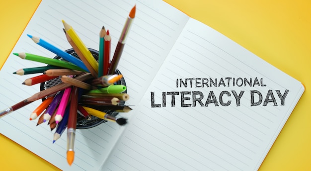 Foto dia internacional da alfabetização. escola estacionária na cesta no livro aberto vista superior fundo amarelo