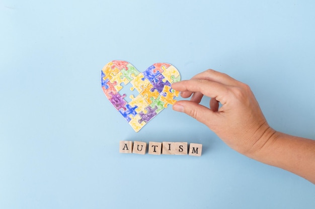 Dia internacional da conscientização do autismo segurando a peça do coração quebra-cabeças