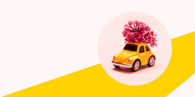 Dia internacional da mulher feliz. brinque o carro amarelo com ramo de flor lilás em um fundo rosa com lugar para texto.