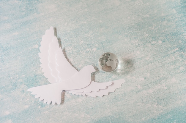 Foto dia internacional do conceito de paz: pomba branca voando em pastel com globo de vidro.