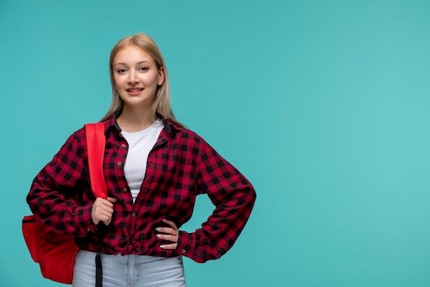 Día internacional de los estudiantes linda chica encantadora en camisa roja a cuadros con una mochila roja