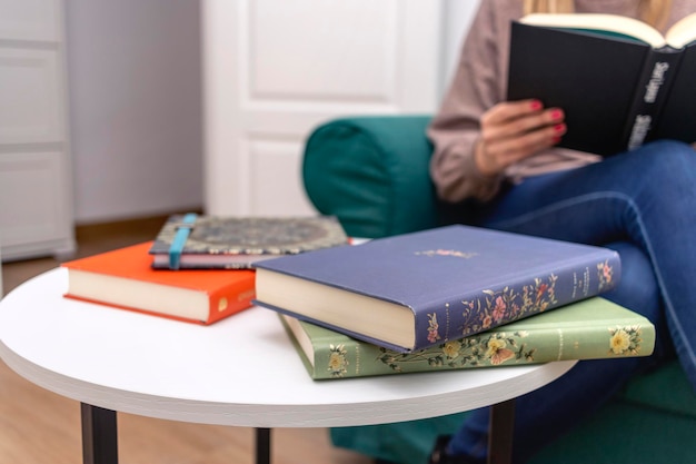 Día Internacional del Libro Libros sobre una mesa con una mujer joven leyendo de fondo