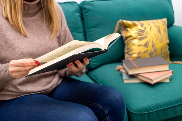 Día Internacional del Libro Mujer joven sentada en un sofá leyendo un libro negro