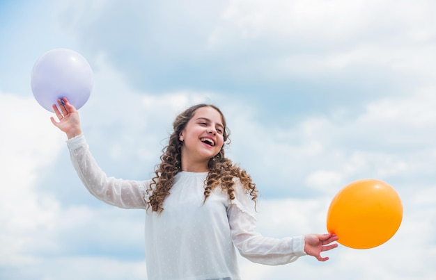 Día internacional de los niños Niño feliz con coloridos globos aerostáticos sobre el fondo del cielo azul expresa emociones positivas simplemente diviértete libertad vacaciones de verano celebración Disfrutando del tiempo de juego