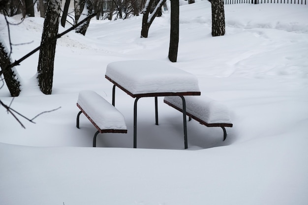 Día de invierno en la ciudad. La nieve se acumula. Mesa y bancos al aire libre bajo una capa de nieve.