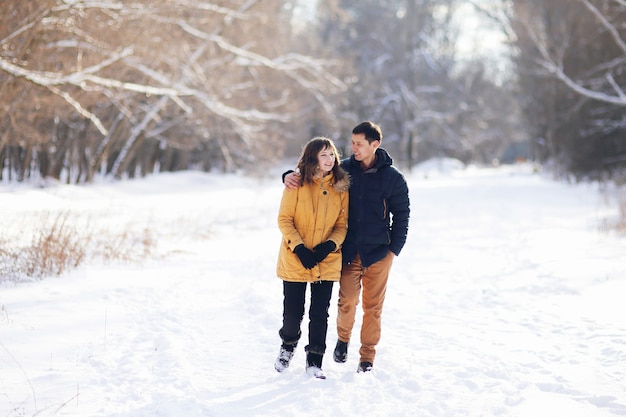 En un día de invierno, una joven pareja camina abrazándose en el parque y se comunica.