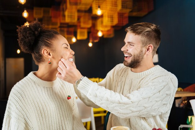 Día juntos. Linda pareja joven sonriendo ampliamente mientras pasan el día juntos desayunando en la cafetería.