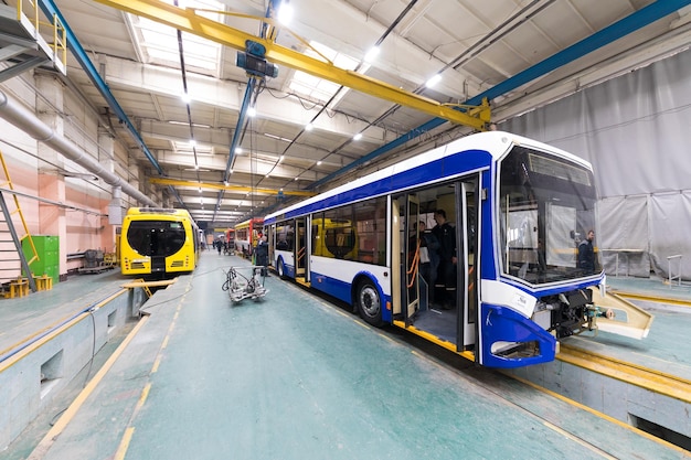 Un día laboral de fabricación de autobuses automáticos modernos con trabajadores de automóviles sin terminar en la producción de automóviles uniformes de protección