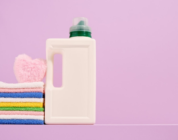 Día de lavado y botella de detergente para la lavandería Toallas lavadas limpias y coloridas y un corazón suave Copiar espacio para el texto