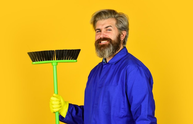 Día de limpieza Agencia de limpieza Trabajador con cepillo Equipo de limpieza Ocupación de jardinero Uniforme azul hipster barbudo con escoba Jardinero hombre de servicio de limpieza Retiro de basura Conserje profesional