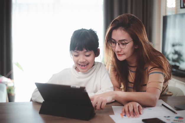 Día de la madre. Niña mirando la computadora portátil con su mamá. Concepto de familia feliz. quedarse en casa