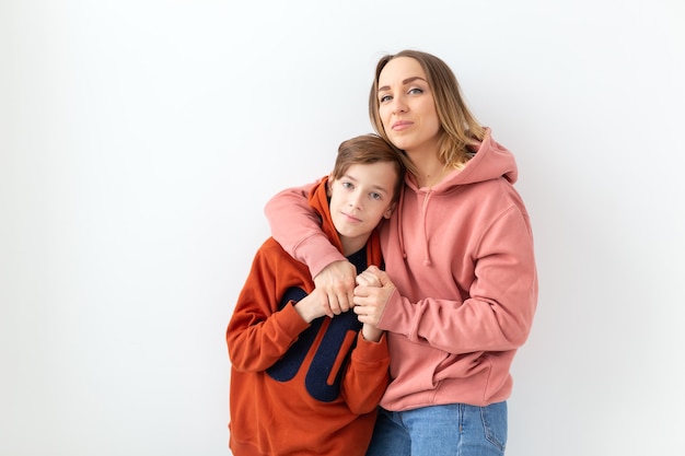 Día de la madre, los niños y el concepto de familia - muchacho adolescente abrazando a su madre en blanco