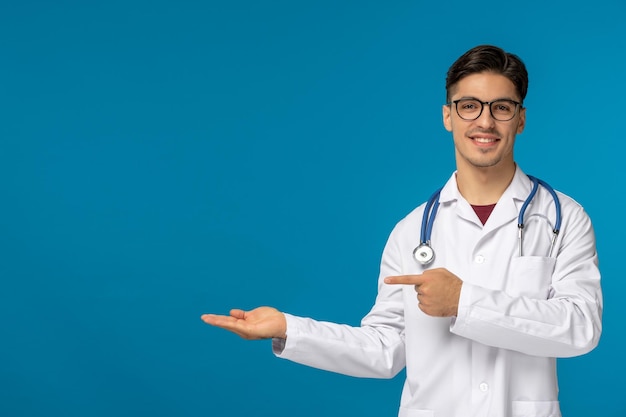 Día de los médicos guapo moreno lindo chico en bata médica sonriendo y con gafas