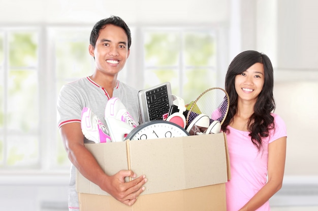 Día de la mudanza. pareja con sus cosas dentro de la caja de cartón