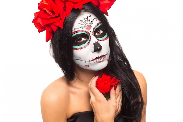 Dia de los Muertos. Festividad de Todos los Santos. Mujer joven en el día de los muertos máscara cráneo cara arte y rosa. Aislado en blanco de cerca.