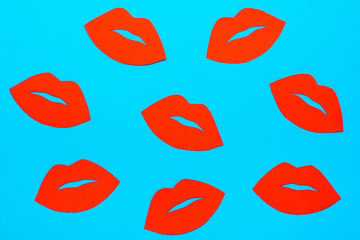 Foto día mundial del beso. muchos labios rojos de cartón sobre un fondo azul.