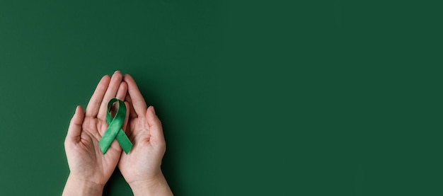 Dia mundial bipolar mãos adultas segurando fita verde dia de conscientização da saúde mental