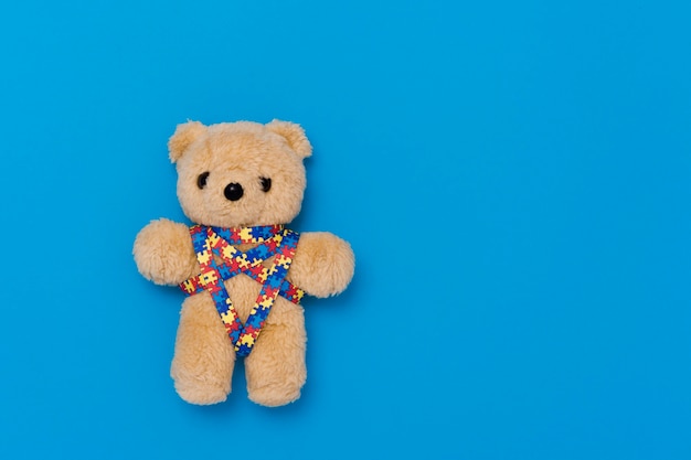 Foto día mundial de concienciación sobre el autismo, concepto de atención de la salud mental con oso de peluche y patrón de rompecabezas de cinta