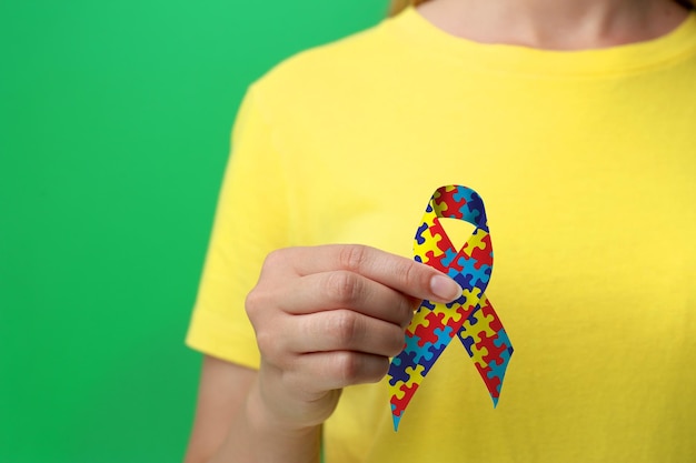 Día Mundial de Concientización sobre el Autismo Mujer con cinta de rompecabezas de colores sobre fondo verde primer plano