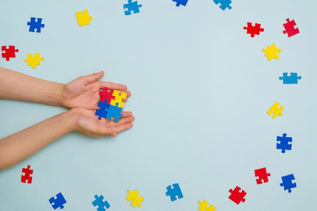 Dia mundial da conscientização do autismo As mãos da criança segurando quebra-cabeças coloridos sobre fundo azul