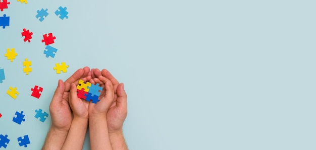 Dia mundial da conscientização do autismo As mãos da criança segurando quebra-cabeças coloridos sobre fundo azul