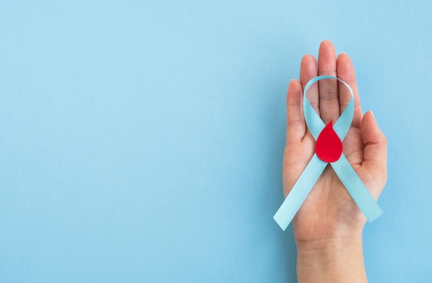 Día mundial de la diabetes. Mano de mujer mantenga conciencia de cinta azul claro