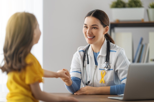 Dia Mundial do Câncer Infantil. Paciente menina ouvindo um médico no consultório médico.