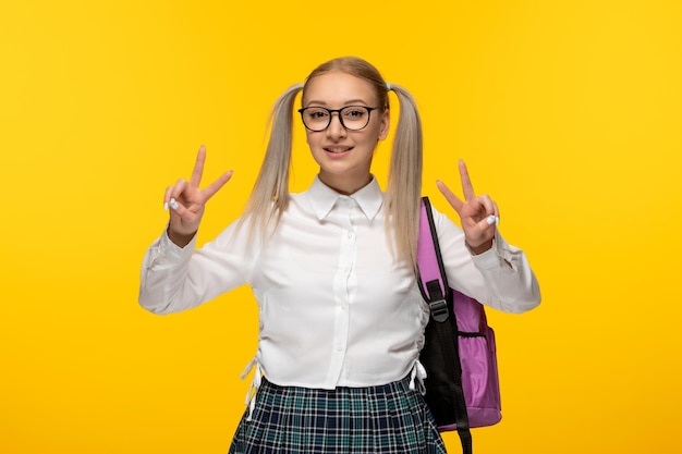 Dia mundial do livro feliz sorridente menina da escola mostrando sinal de gesto de paz