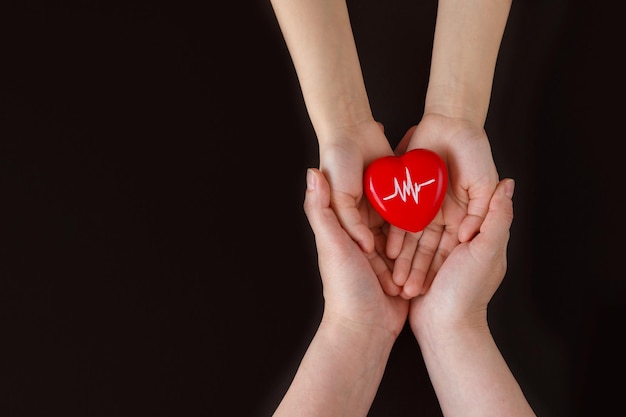 Día Mundial de la Hipertensión Adulto y niño sosteniendo un corazón rojo con un gráfico de latidos con sus manos