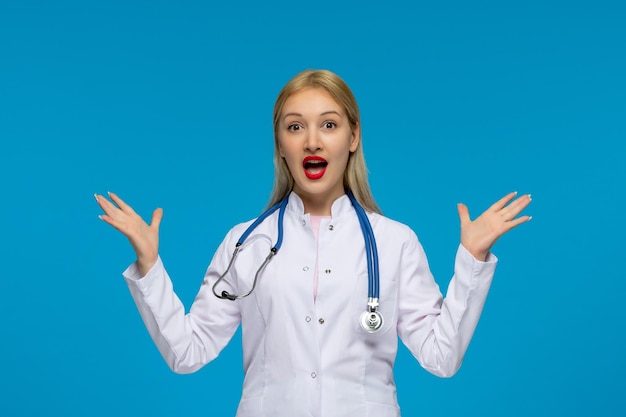 Día mundial del médico emocionada joven doctora rubia con el estetoscopio en la bata de laboratorio