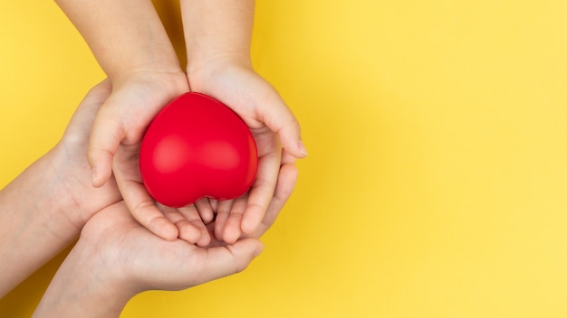 Día mundial de la salud, manos de adultos y niños con corazón rojo, atención médica, amor y concepto de seguro familiar