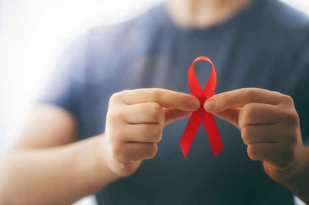 Foto día mundial del sida. cinta roja en las manos de cerca