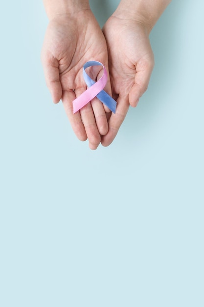 Día Mundial de la Tiroides Manos adultas sosteniendo cinta de concientización sobre el cáncer de tiroides en Teal Pink Blue