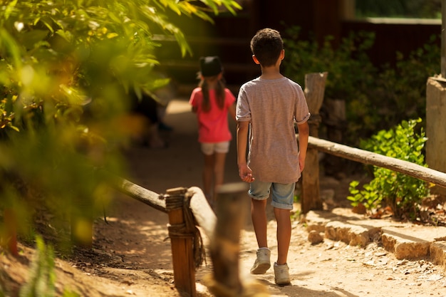 Día del Niño. Pequeño niño y una niña corriendo en el parque. Vista trasera