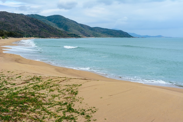 Día nublado, playa desierta de arena de la costa cerca de la estatua de la diosa Nanshan en el Mar de China Meridional. Sanya, isla de Hainan, China. Paisaje de la naturaleza.