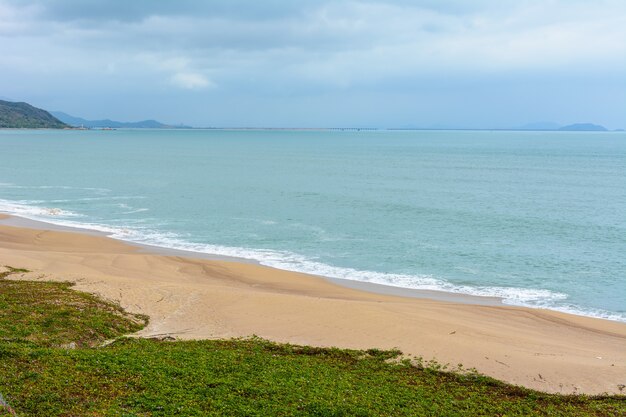 Dia nublado, praia deserta de areia da costa perto da estátua da deusa Nanshan no mar da China Meridional. Sanya, ilha de Hainan, China. Natureza Paisagem.