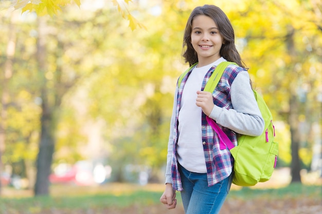 Este día de otoño. niño camina en el bosque de otoño. hojas de otoño en el parque. clima estacional. felicidad infantil. belleza y naturaleza. niño feliz usa estilo casual. adolescente lleva mochila de camino a la escuela.