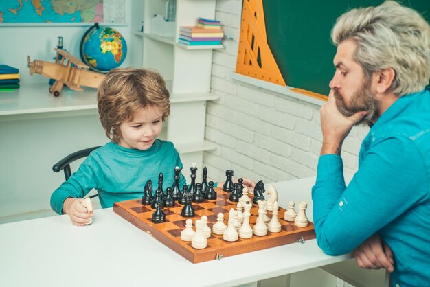 Día del padre niño concentrado desarrollando estrategia de ajedrez niño inteligente concentrado y pensante mientras